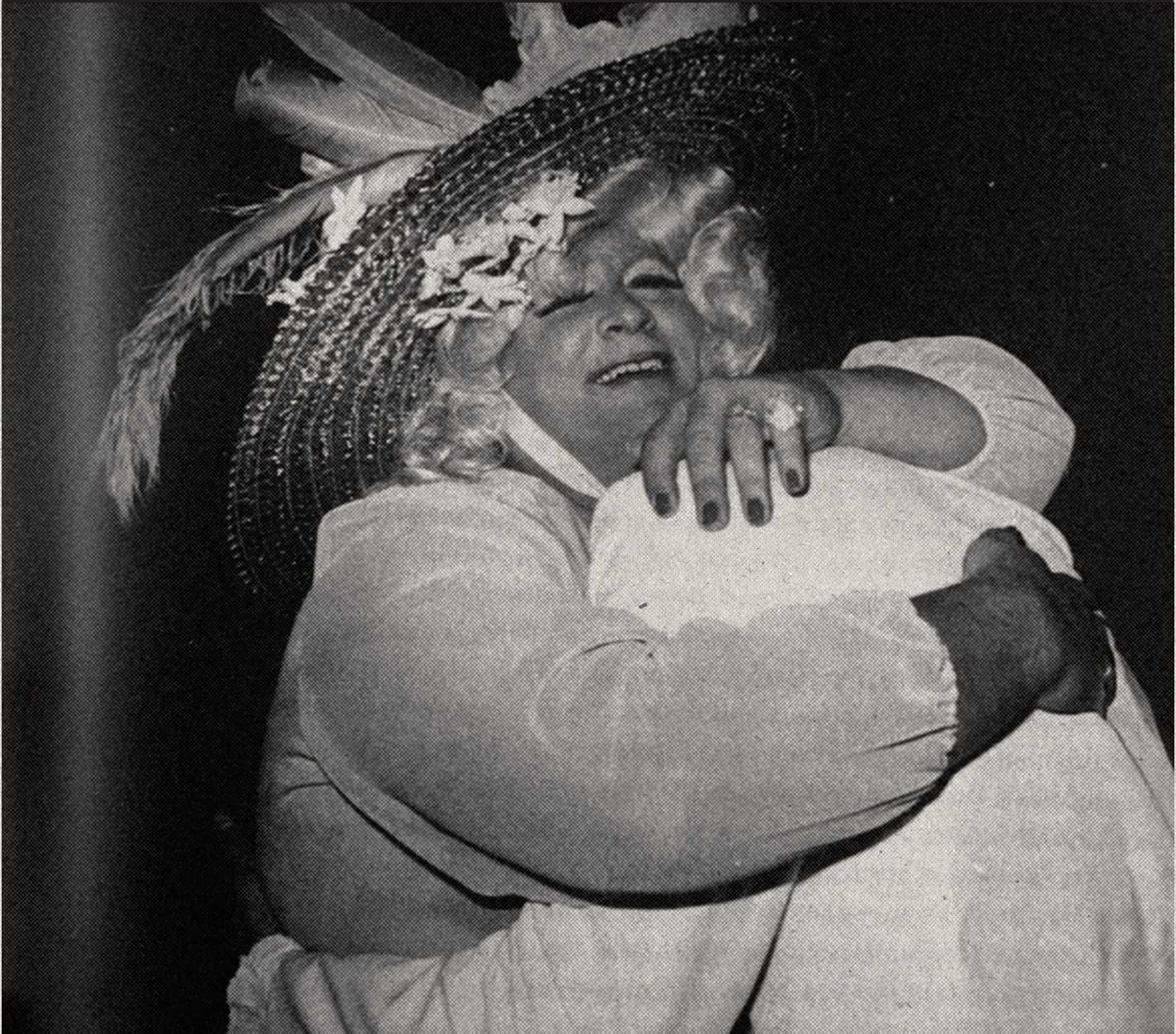 Mother Carol in a flowered hat, embracing a friend