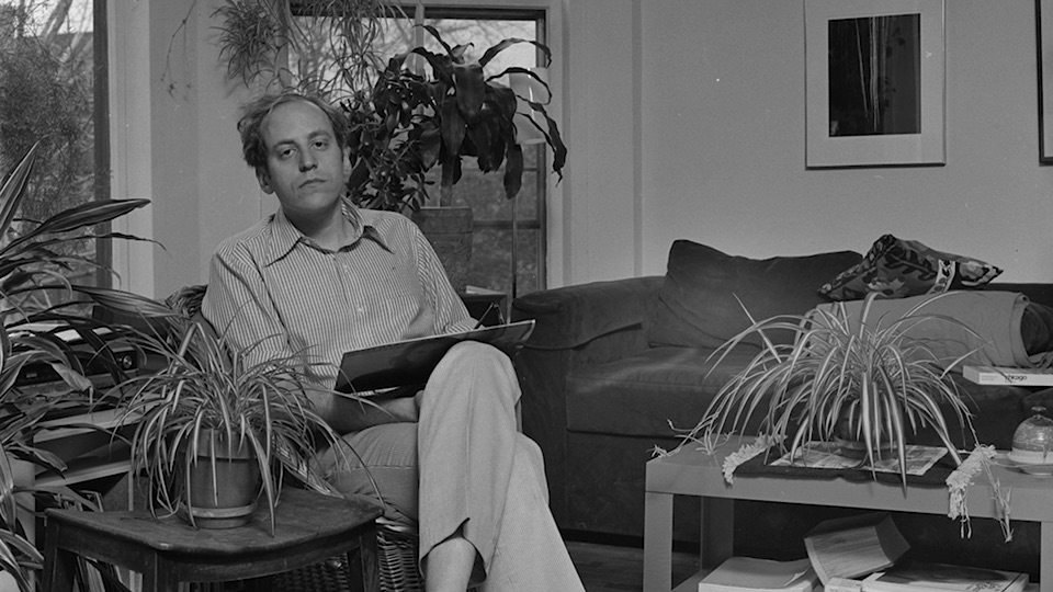 Grant Pick, reporter, seated at home with a notebook, black-and-white photograph